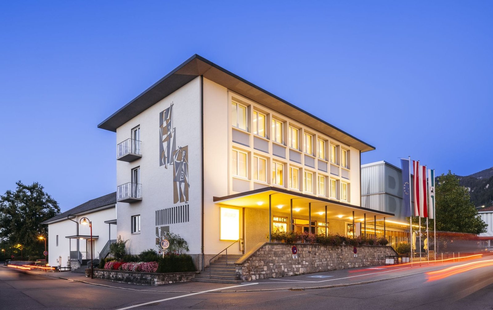 Kulturbühne Ambach in Götzis zur blauen Stunde, Außenansicht mit beleuchtetem Eingang